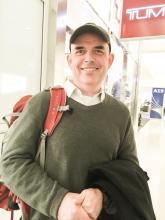 headshot of Andy Wood, a white man wearing a sweater, cap, and backpack